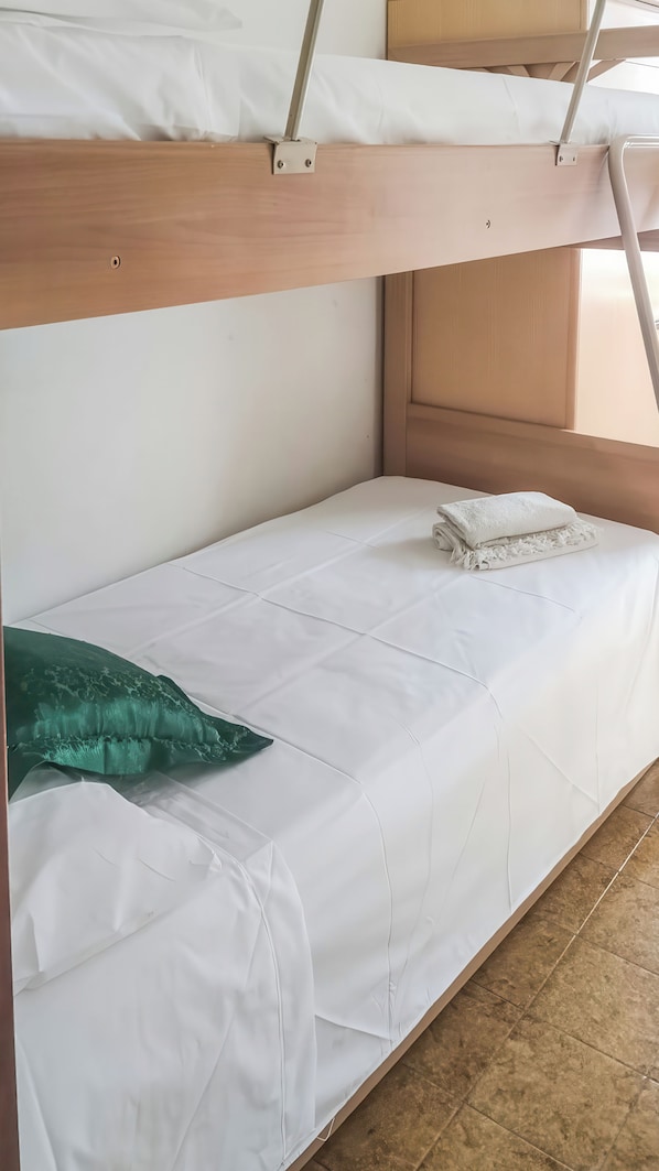 A bunk bed with white bedding and a green pillow. - Eden Scalea (Scalea)