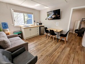 Eine moderne Küche mit Essbereich, Holzboden und einem an der Wand montierten Flachbildfernseher.