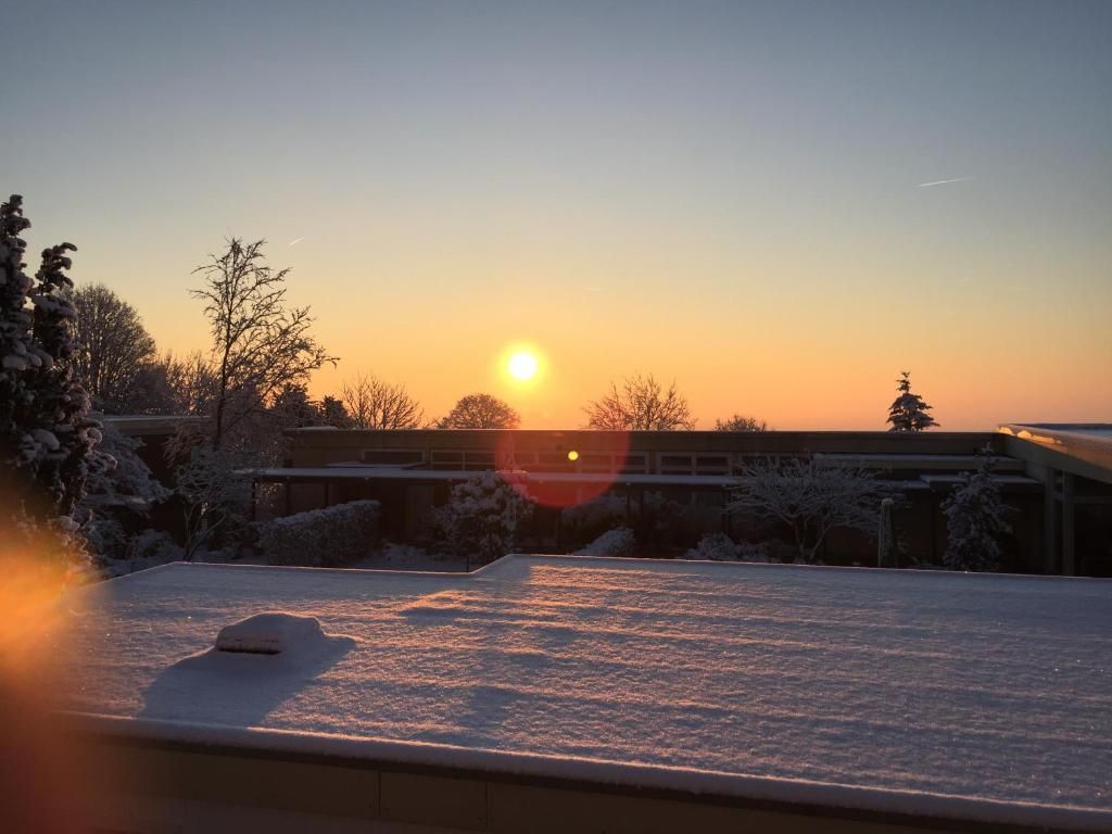 Un toit enneigé, avec un coucher de soleil en arrière-plan.