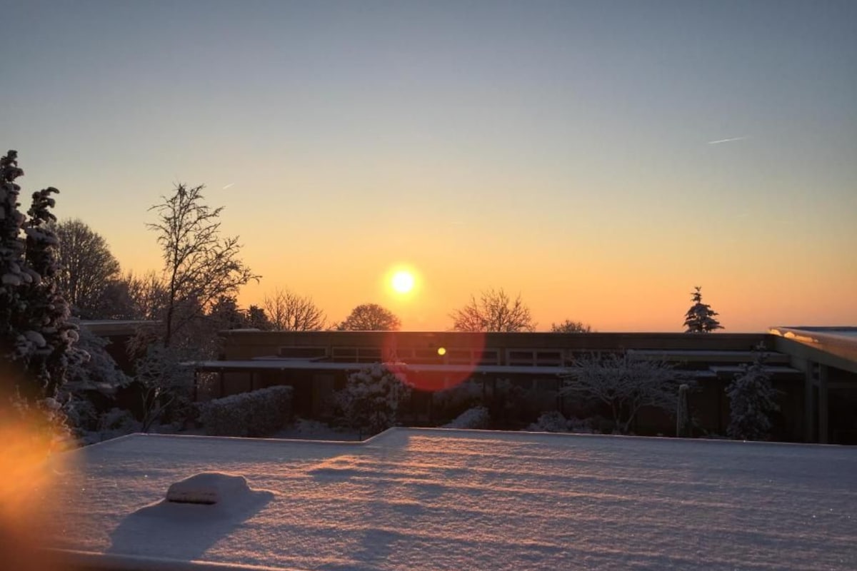 Telhado coberto de neve com um pôr do sol ao fundo.