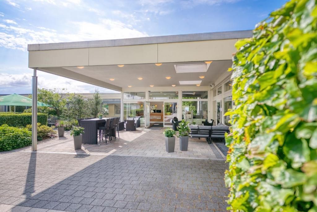 An outdoor seating area with tables and chairs, a covered walkway, and potted plants.