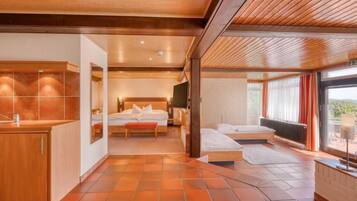 A modern hotel room with a wooden ceiling, a large bed with a headboard, a bedside table, and a view through a glass door.