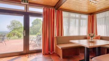A room with a bench, a table, and a view through a glass door.