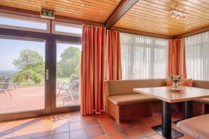 Quarto com um banco, uma mesa e vista através de uma porta de vidro.