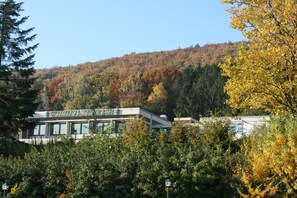 A building with a sign that reads 'VANCOUVER'S SITTING ROOM' amidst a forested hillside.