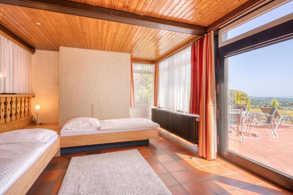 Un dormitorio con techo de madera, pared de ladrillo, un ventanal y vista al exterior.