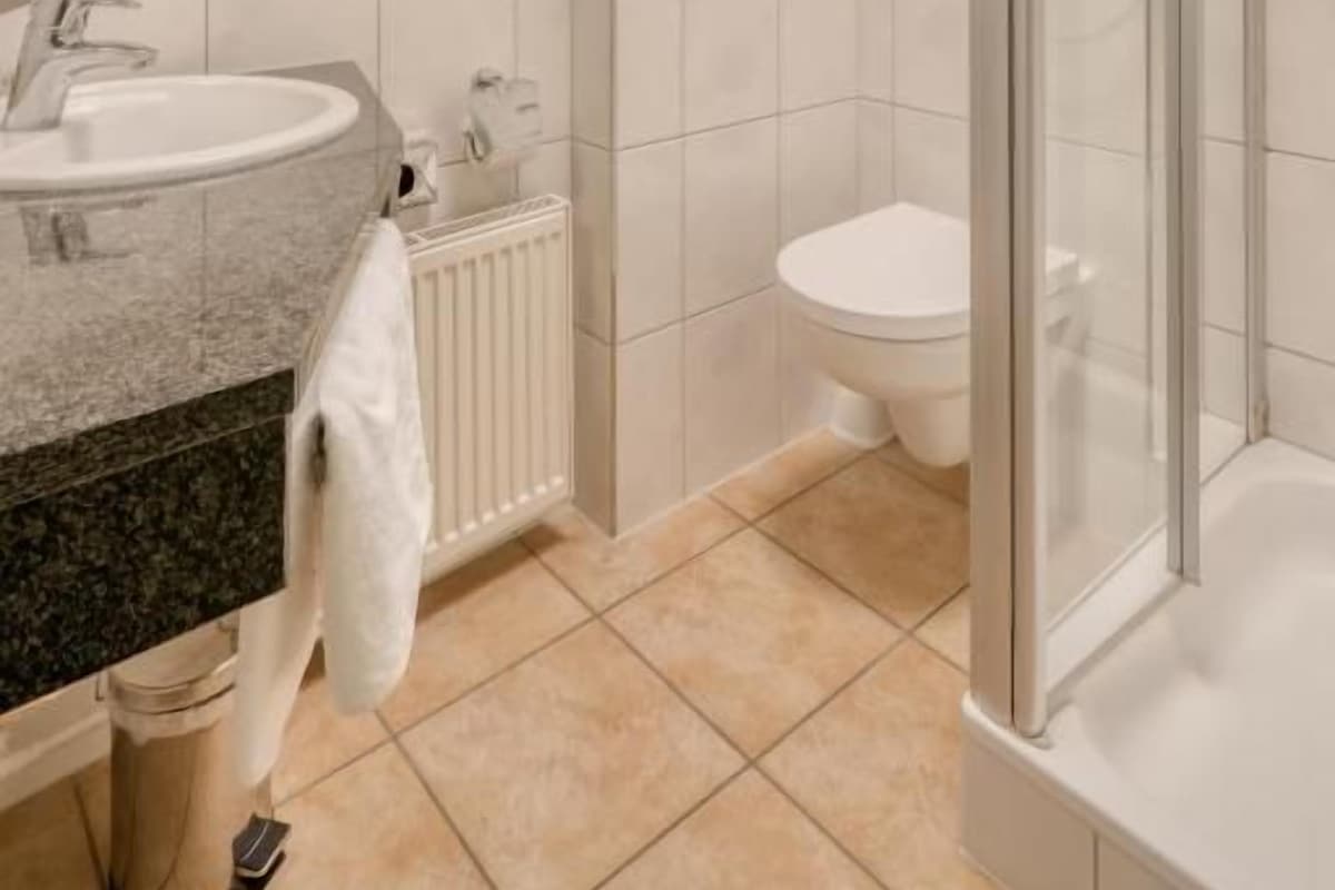 A modern bathroom with a glass-enclosed shower, a sink, and a toilet.