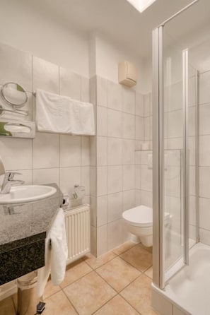 A modern bathroom with a glass-enclosed shower, a sink, and a toilet. - Hotel Wiehen-Therme GmbH & Co. KG (Hüllhorst)