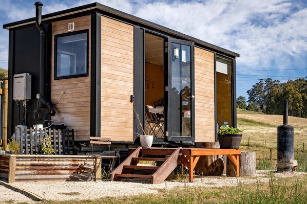 Une cabane moderne avec une façade en bois, de grandes fenêtres et une cheminée.