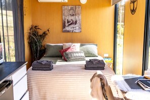Une chambre à coucher avec un lit, des oreillers, une table de chevet, une plante et un élément décoratif mural.