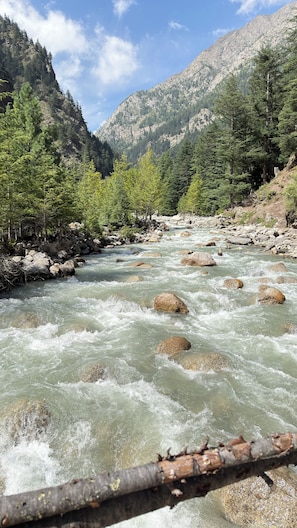 A river with rocks and trees, surrounded by mountains.