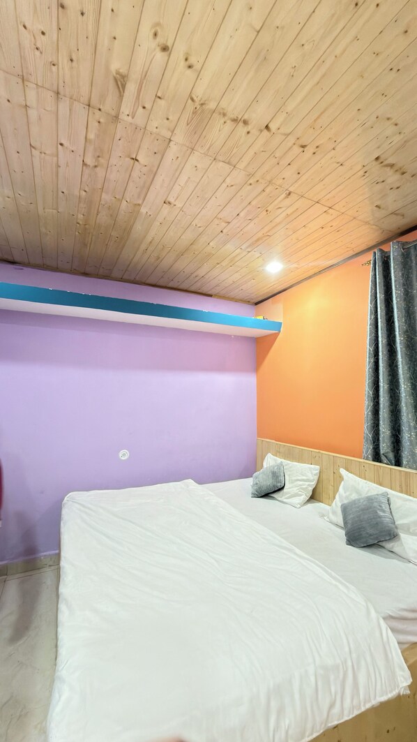 A bedroom with a wooden ceiling, a bed with white bedding, and a purple wall.