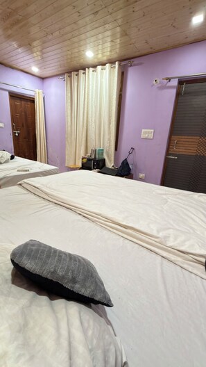 A bedroom with two beds, a wooden ceiling, and a purple wall.