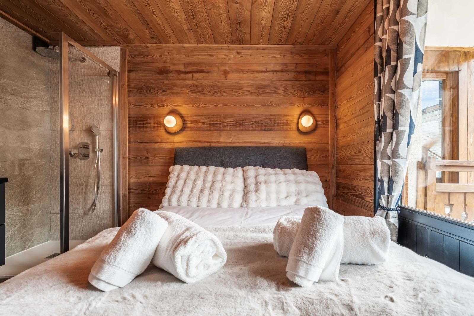 Ein Zimmer mit Holzboden, einem Bett, zwei Wandleuchten und einer Dusche.