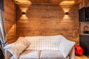 A cozy room with a wooden wall, a cushioned bench, and a red decorative object. - Val Thorens: Cozy Apartment in the Heart of the Resort (Les Belleville)