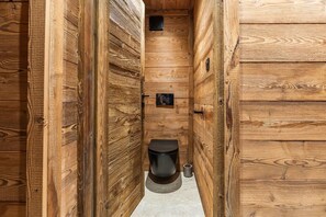 A narrow wooden hallway leading to a small, enclosed bathroom with a toilet and a wall-mounted heater. - Val Thorens: Cozy Apartment in the Heart of the Resort (Les Belleville)