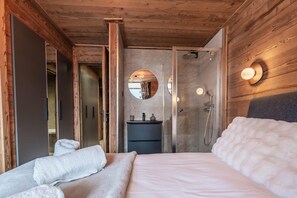 A bedroom with a bed, a bedside table, a mirror, a shower, and a wardrobe. - Val Thorens: Cozy Apartment in the Heart of the Resort (Les Belleville)