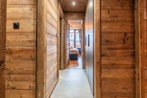 A wooden hallway leading to a bedroom with a bed and a window. - Val Thorens: Cozy Apartment in the Heart of the Resort (Les Belleville)