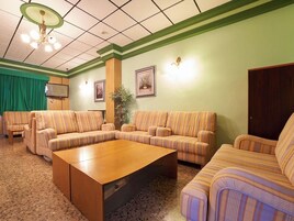 Una sala de estar con sofás a rayas, una mesa de centro de madera y una cortina verde.