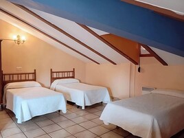 Habitación con dos camas, techo inclinado y lámpara fijada a la pared.