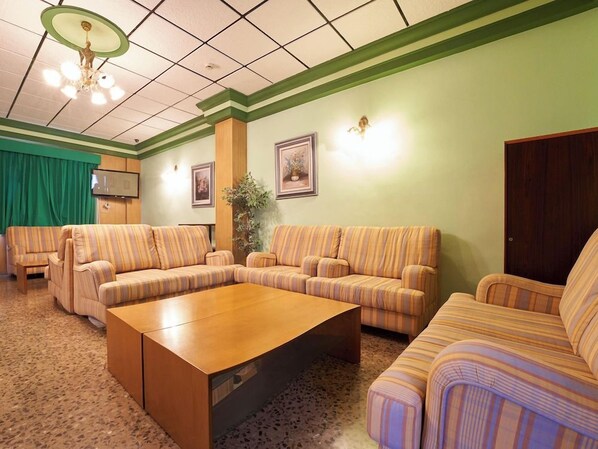 A living room with striped sofas, a wooden coffee table, and a green curtain.