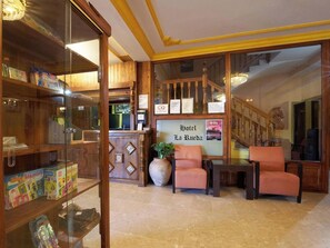 A hotel lobby with a reception desk, a staircase, and seating area.