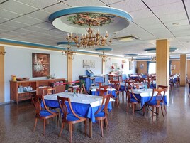 Un comedor amplio con varias mesas y sillas, una araña y un techo con diseño decorativo.
