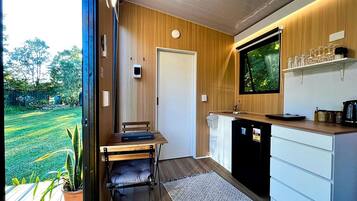 A compact kitchen with a dining area, a built-in TV, and a view of a green landscape.