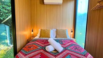 Une chambre moderne avec un grand lit, un plafond en bois et une vue sur la verdure environnante.