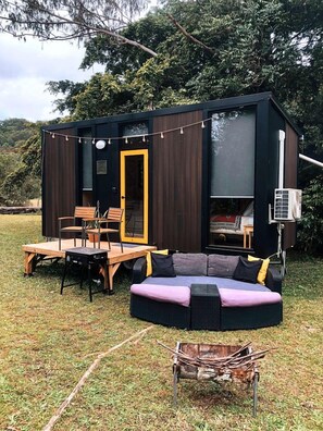 A modern outdoor living space with a built-in seating area, a table, and chairs. - Tranquil Tiny Cabin Retreat with Stargazing near Sunshine Coast, Yandina QLD (Nambour)