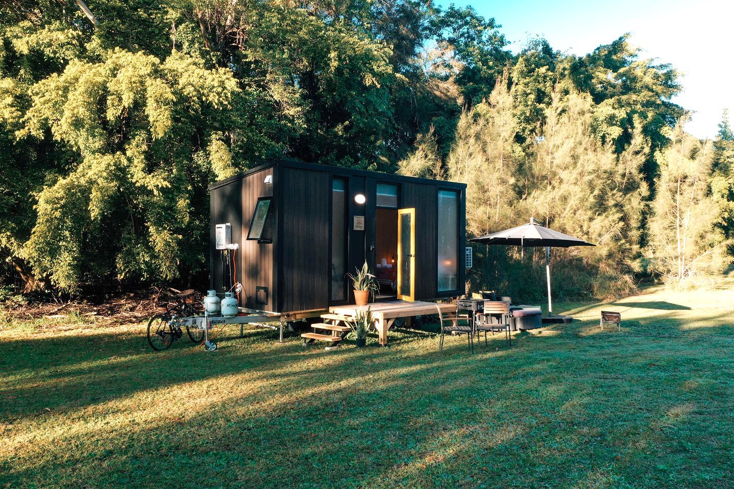 Une petite cabane dotée d’une terrasse, entourée d’arbres.