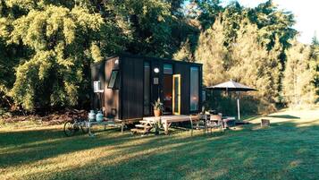 Une petite cabane dotée d’une terrasse, entourée d’arbres.