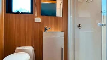 A compact bathroom with a toilet, sink, and shower.