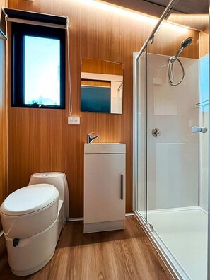 A compact bathroom with a toilet, sink, and shower. - Tranquil Tiny Cabin Retreat with Stargazing near Sunshine Coast, Yandina QLD (Nambour)