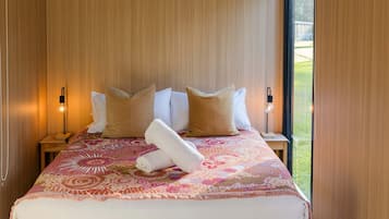 A hotel room with a bed, pillows, a rolled towel, and two bedside lamps.