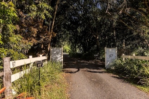 A rural road leading to a gated entrance with a number 67 sign.