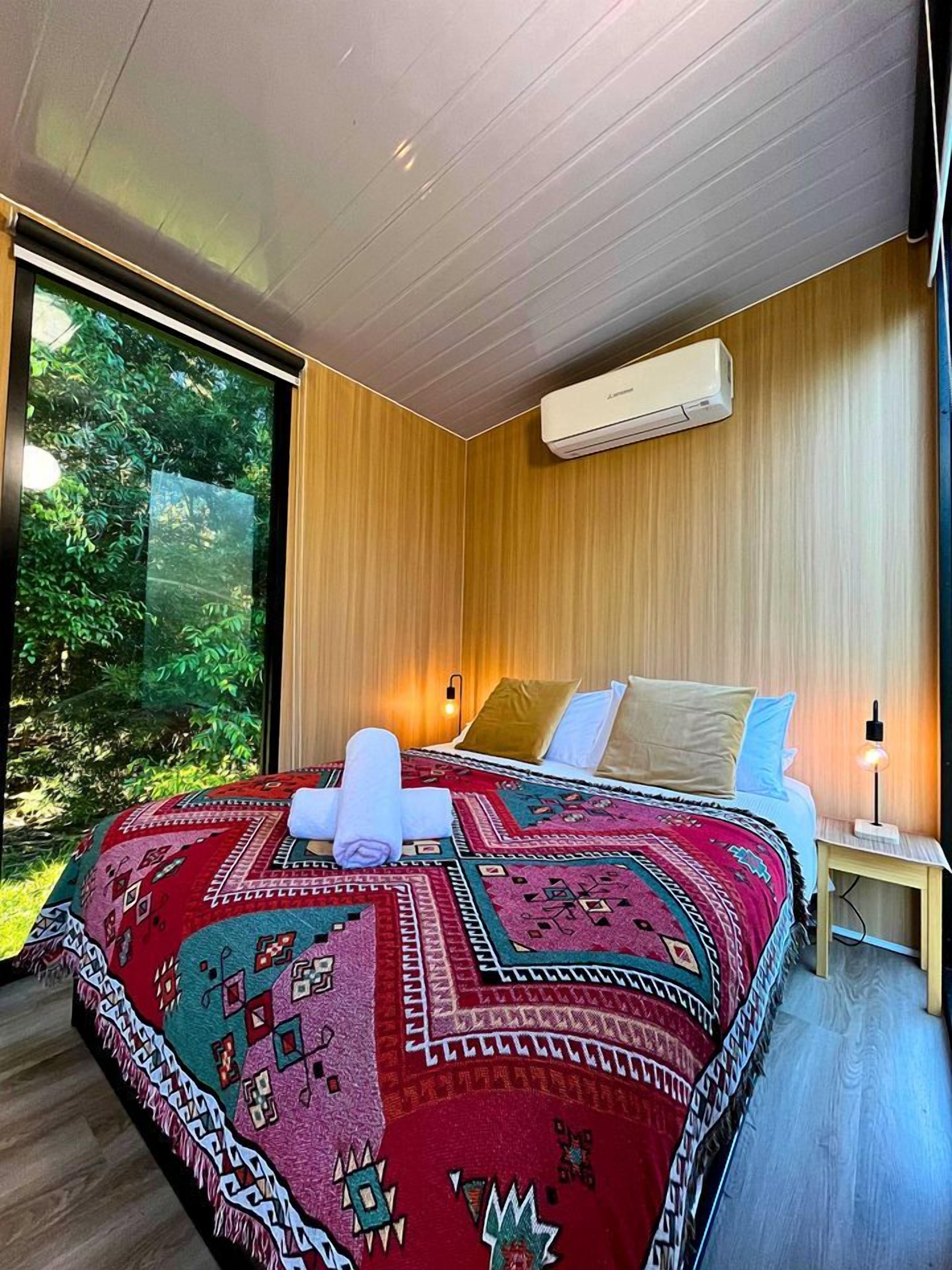 Une chambre moderne avec un grand lit, une fenêtre et un climatiseur fixé au mur.
