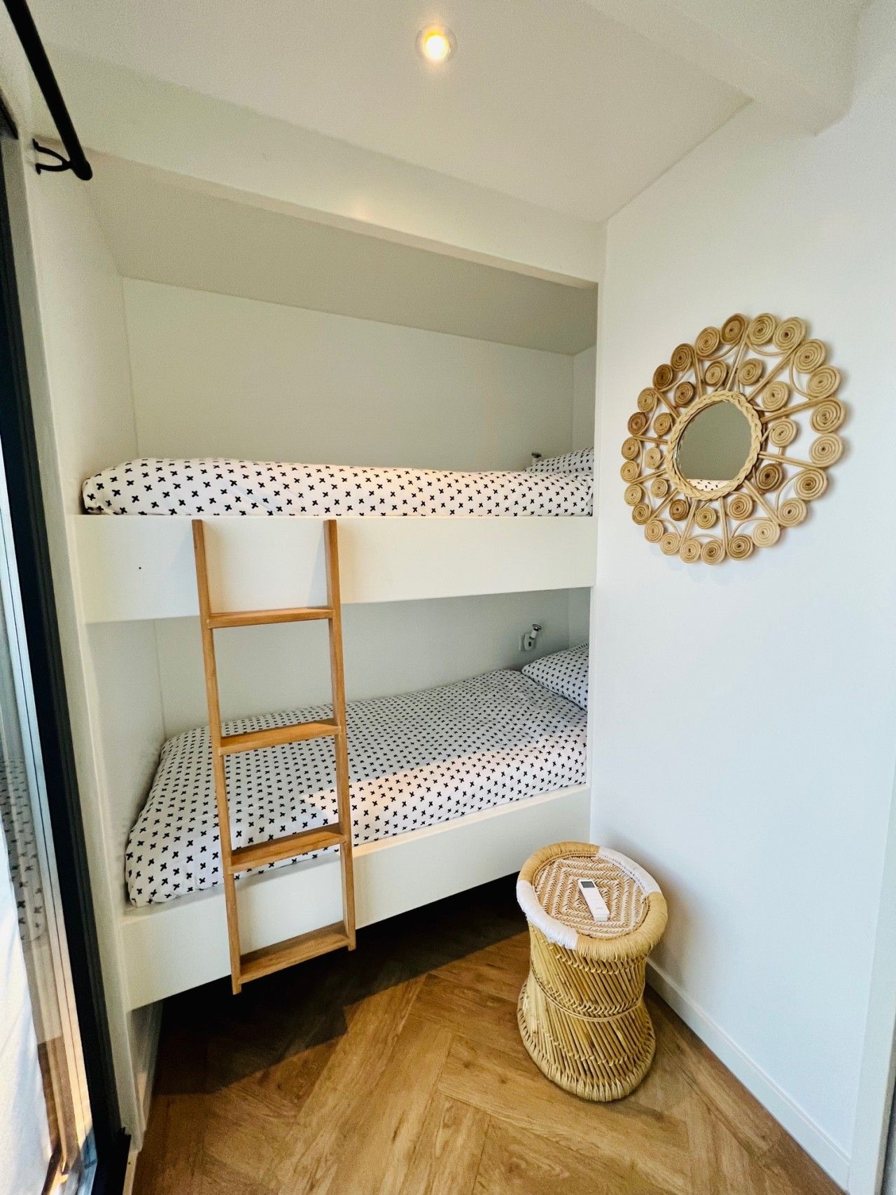 Ein Stockbett mit einer Leiter, einem gewebten Korb und einem an der Wand befestigten Spiegel.