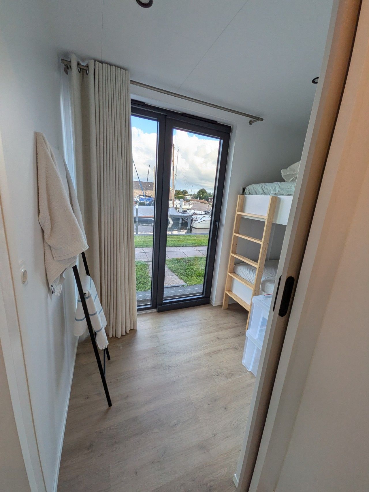 Ein Zimmer mit einem Etagenbett, einer Schiebetür zum Balkon und einem Handtuchhalter.