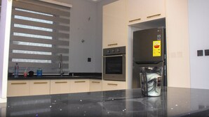 Een moderne keuken met een inbouwoven, een koelkast en een raam met zonwering.