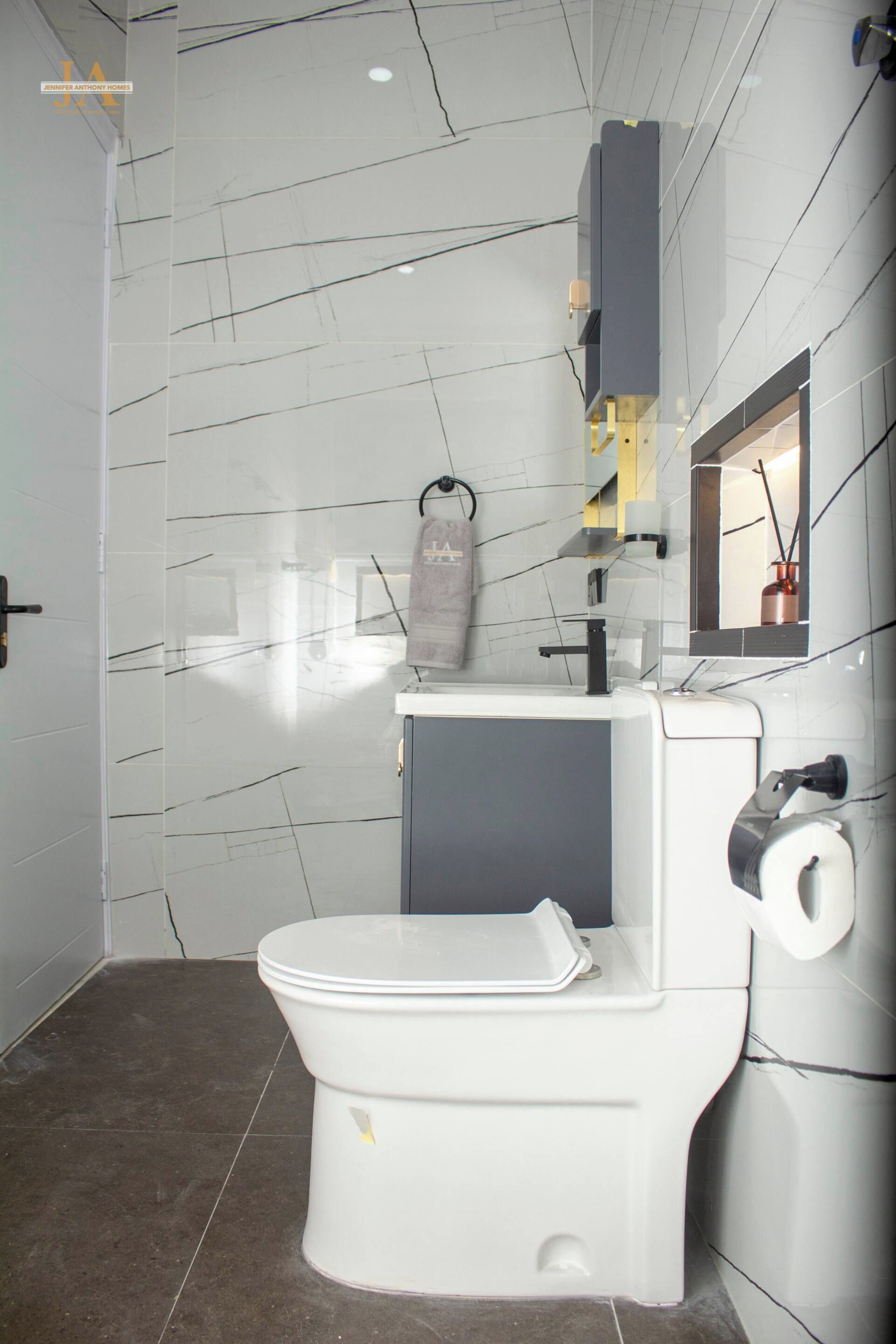 Ein modernes Badezimmer mit Toilette in Weiß, einem grauen Schrank und einem Spiegel.