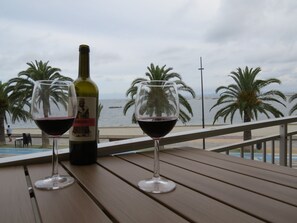 A bottle of wine and two glasses on a wooden table with a view of the sea and palm trees. - Beachfront Dos Nanitos, right on the beach. Private parking. Pets welcome! (San Pedro del Pinatar)