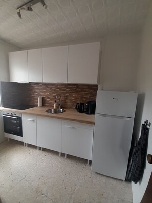 A modern kitchen with white cabinets, a wooden countertop, a sink, a stove, and a refrigerator. - Beachfront Dos Nanitos, right on the beach. Private parking. Pets welcome! (San Pedro del Pinatar)