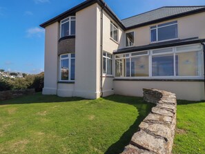 A two-story house with a stone wall and a grassy yard. - Chy-an-lowena (Newquay)
