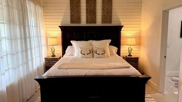 A large bed with a dark headboard, two bedside lamps, and decorative wall panels.