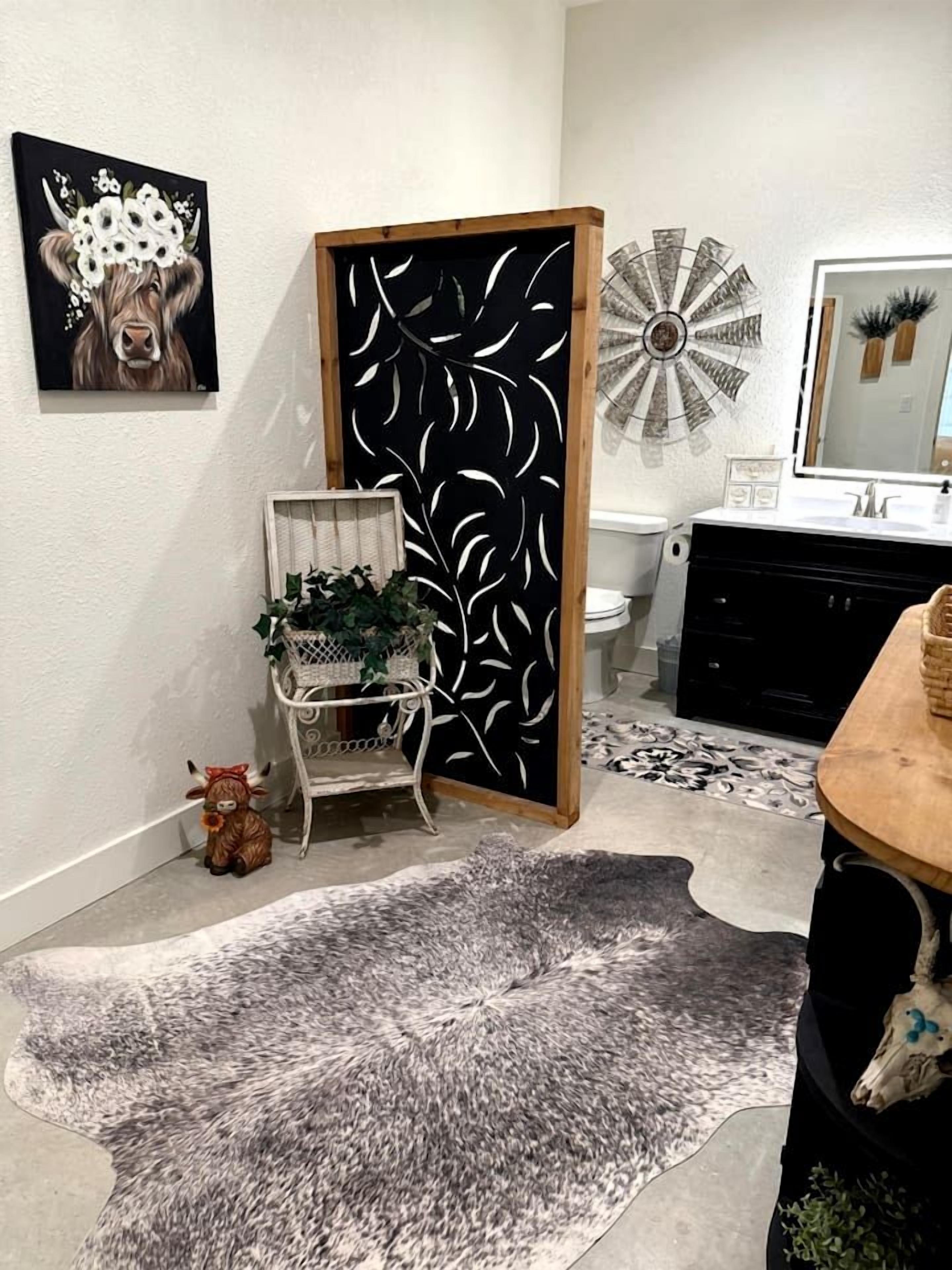 Un bagno con lavandino bianco, uno specchio e un elemento decorativo a parete.