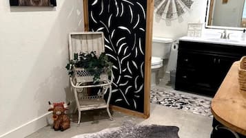 Un bagno con lavandino bianco, uno specchio e un elemento decorativo a parete.