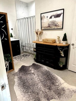 Een kamer met een zwarte console tafel, een lijst met een afbeelding aan de muur, en een grijs plooien tapijt.