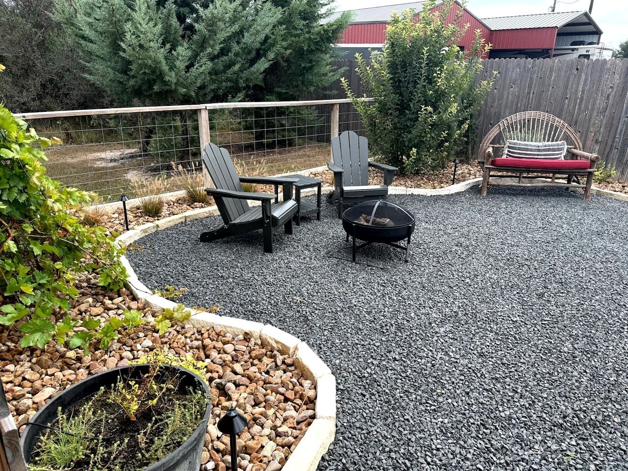 A backyard with a fire pit, Adirondack chairs, and a wooden bench.