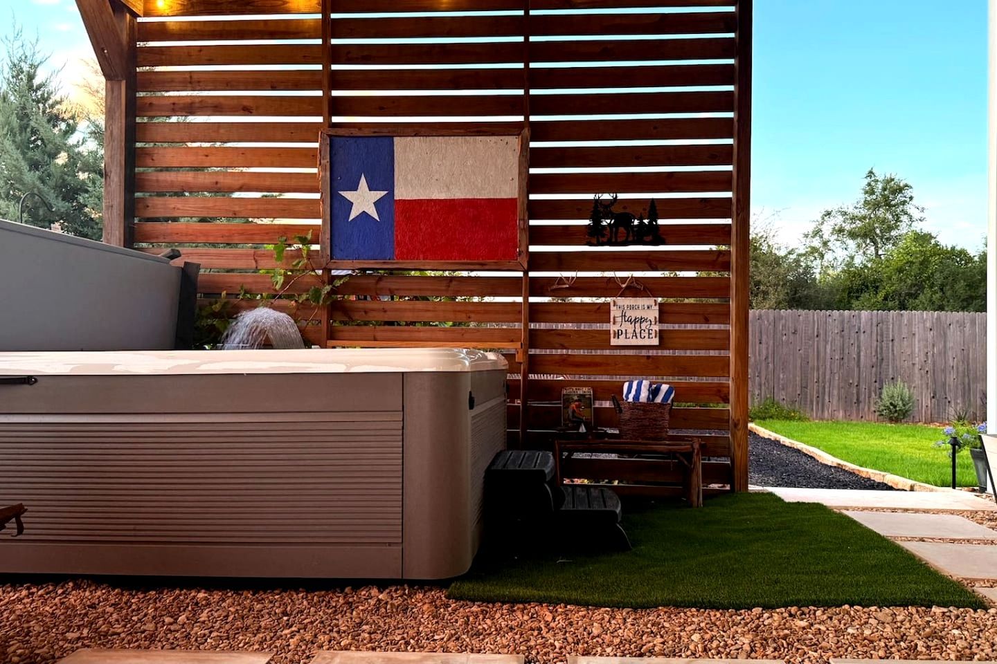 A patio area with a hot tub, a wooden fence, and a Texas flag.